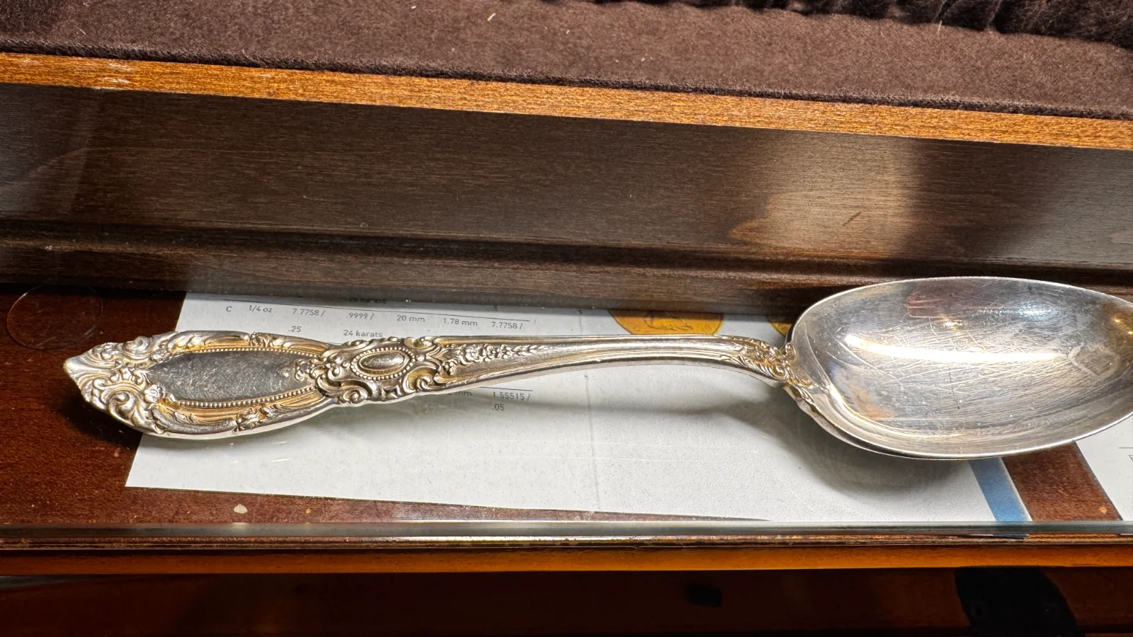 ornate silver spoon with floral engravings on handle laying on paper
