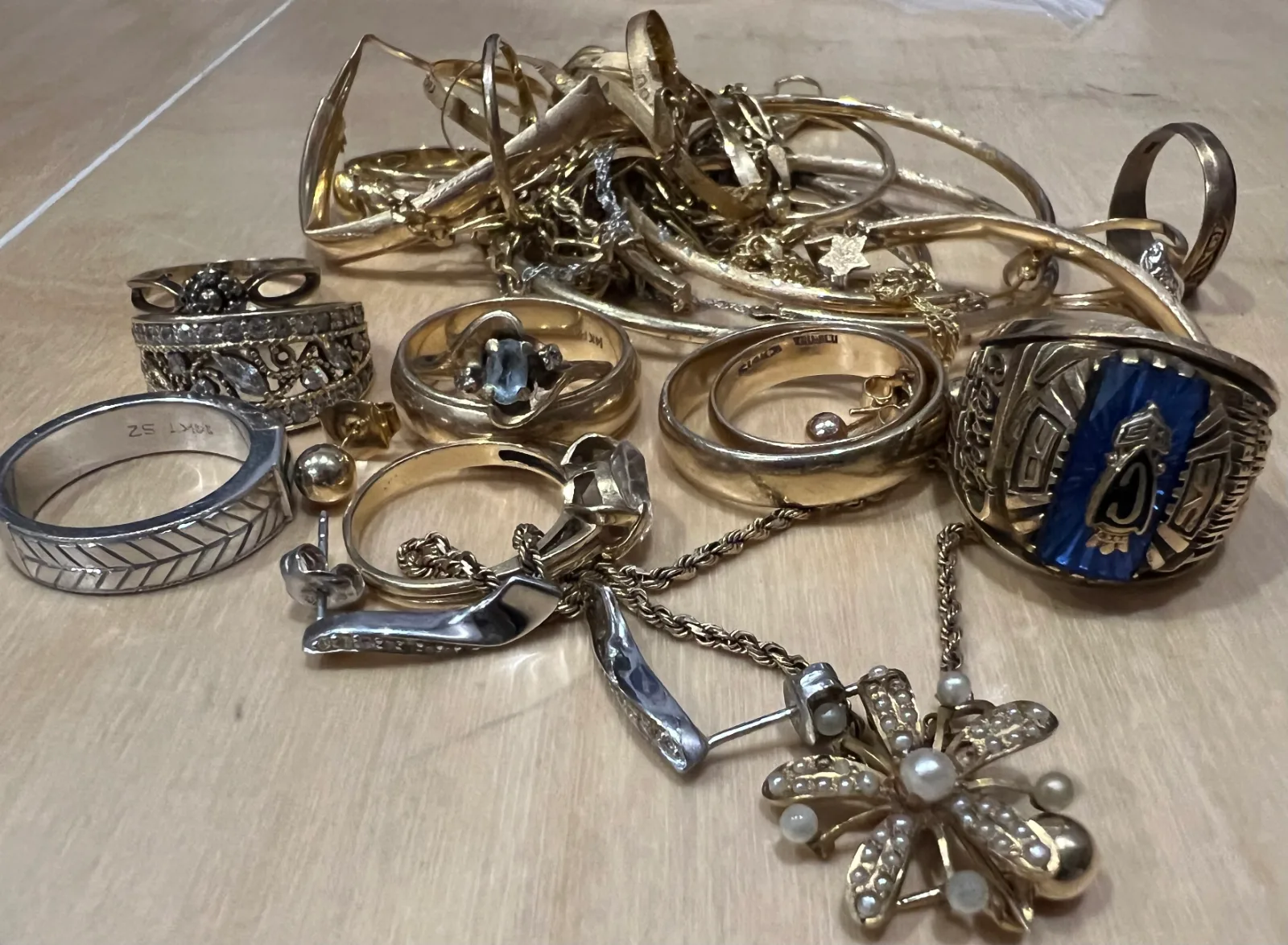 various gold and silver rings necklaces and earrings piled on a table