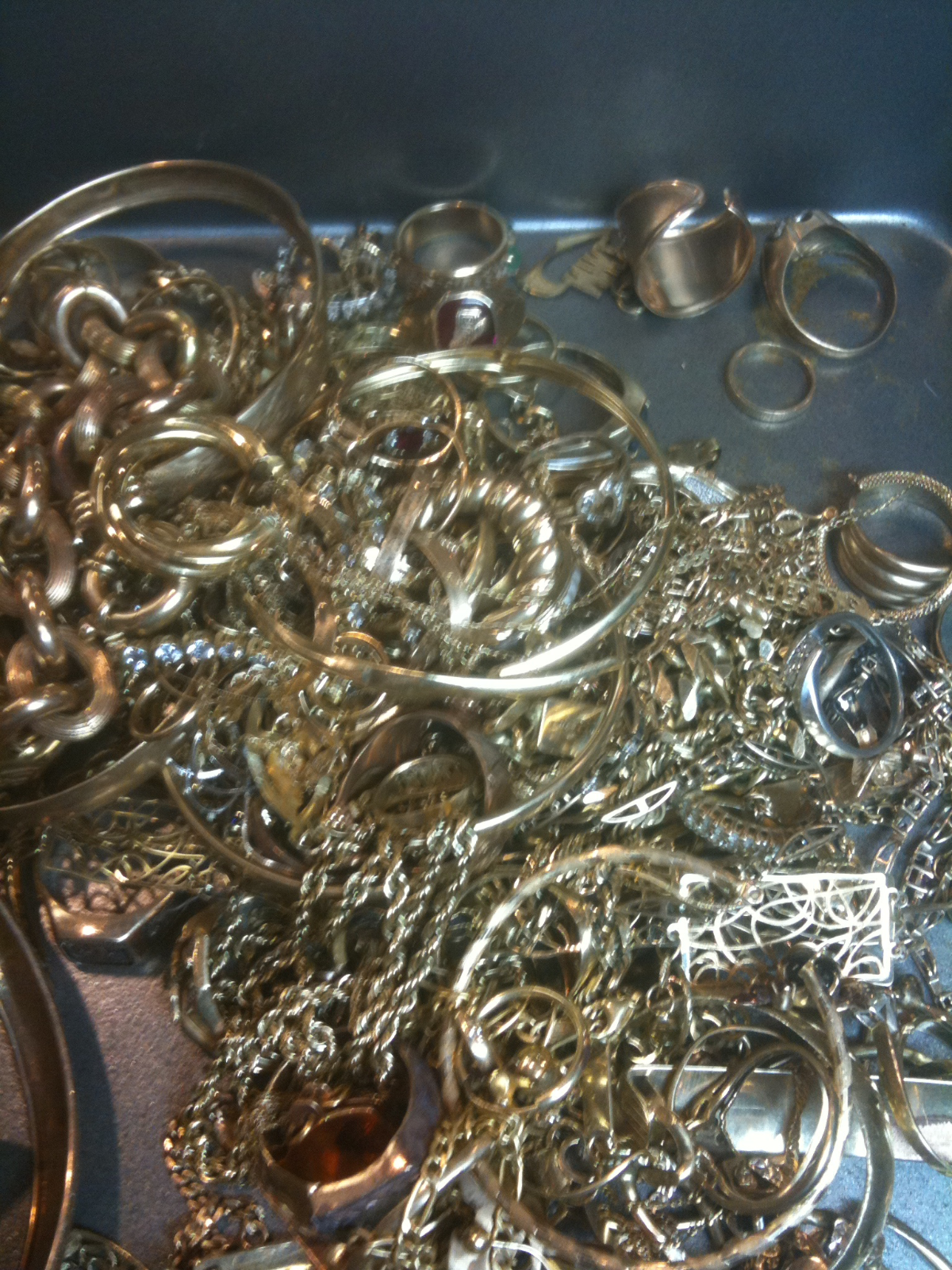 tangled pile of gold and silver jewelry including chains rings and bracelets