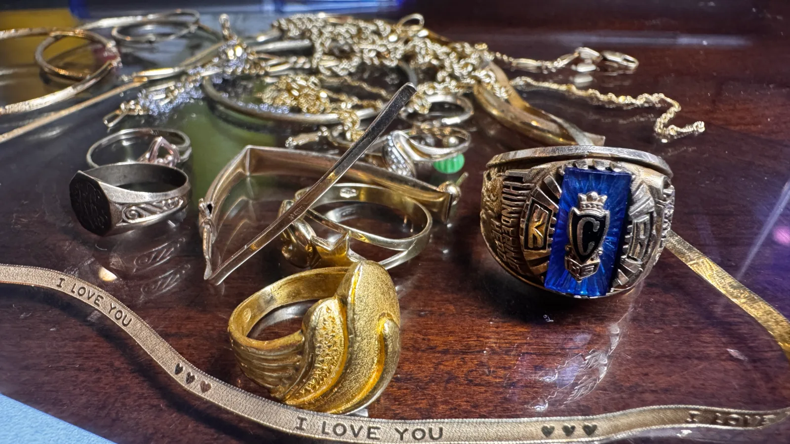 assorted gold and silver rings and chains on a wooden surface