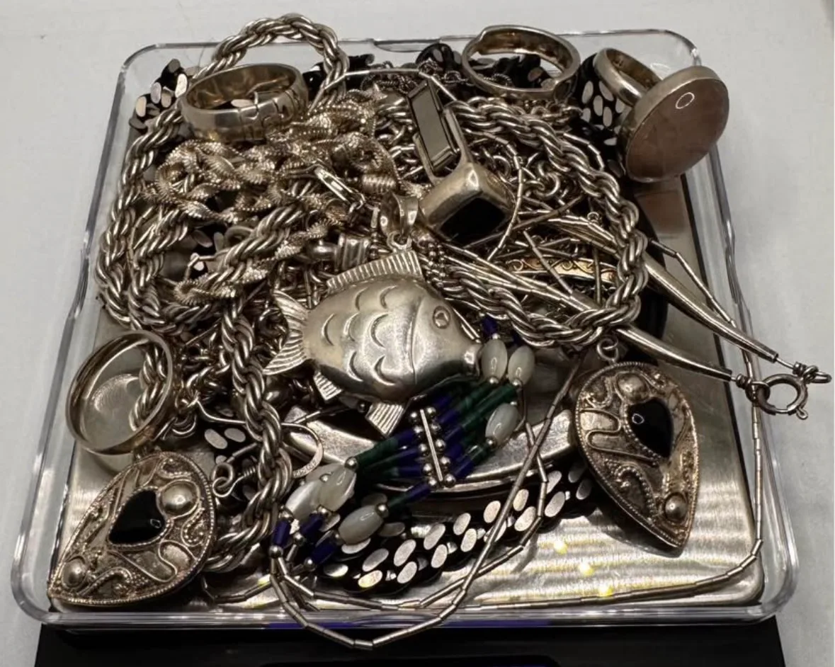 Tangled pile of silver chains rings and pendants on a digital scale