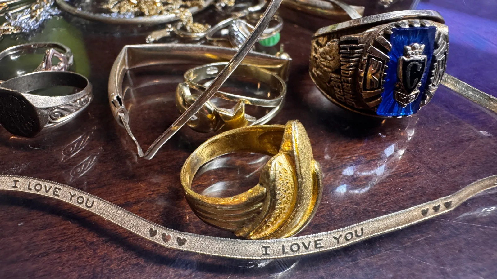 various gold and silver rings and necklaces on a dark wooden surface