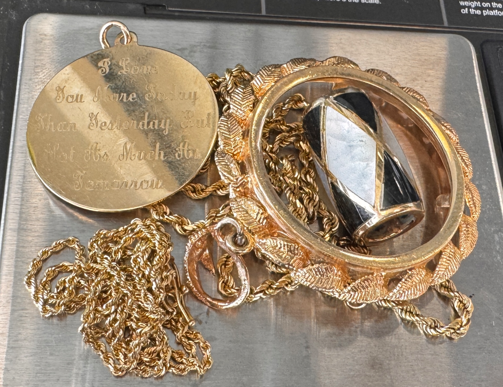 gold jewelry including a chain engraved pendant and a bezel on a scale