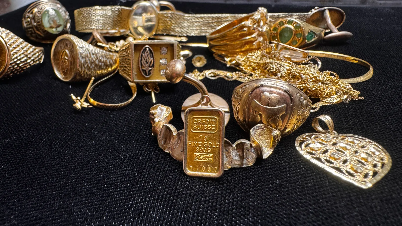 collection of gold jewelry rings and pendants on black surface