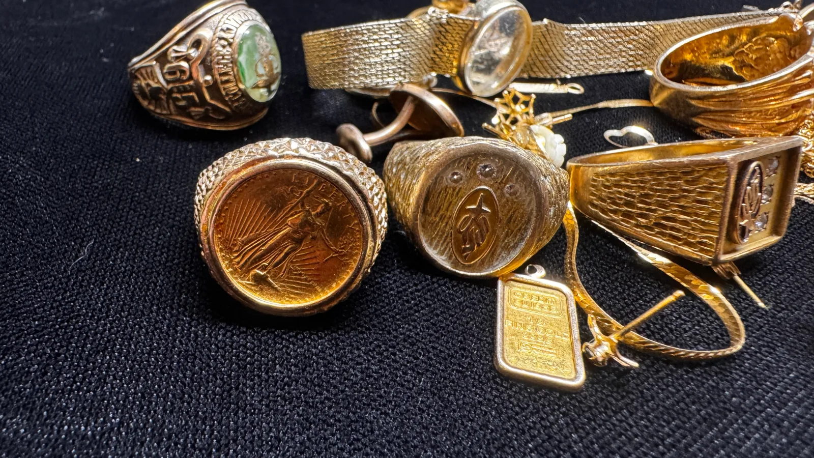 collection of gold rings watches and jewelry scattered on black surface
