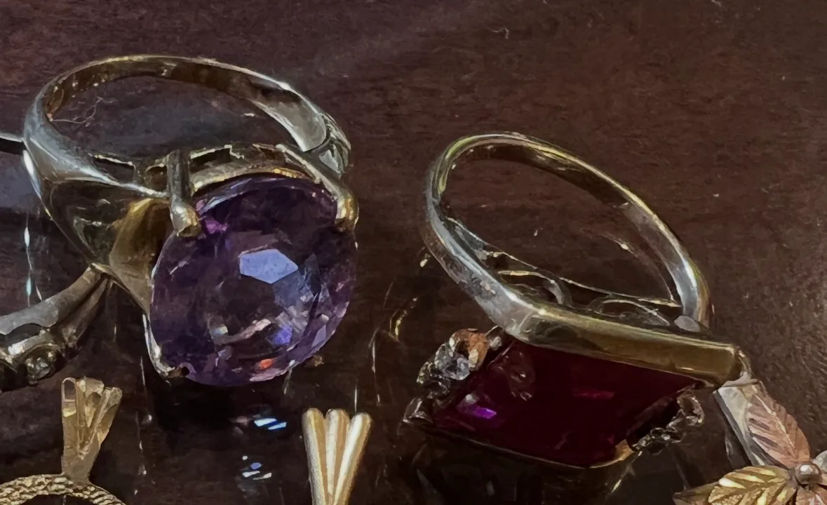 gold rings with large purple and red gemstones on dark surface