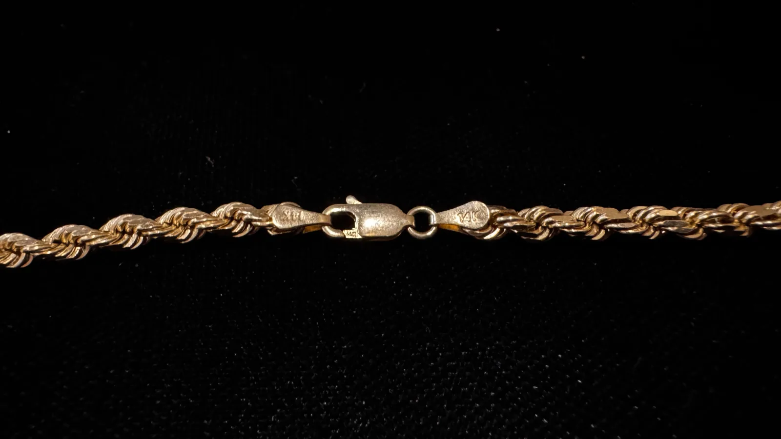 gold rope chain necklace with lobster claw clasp on black background