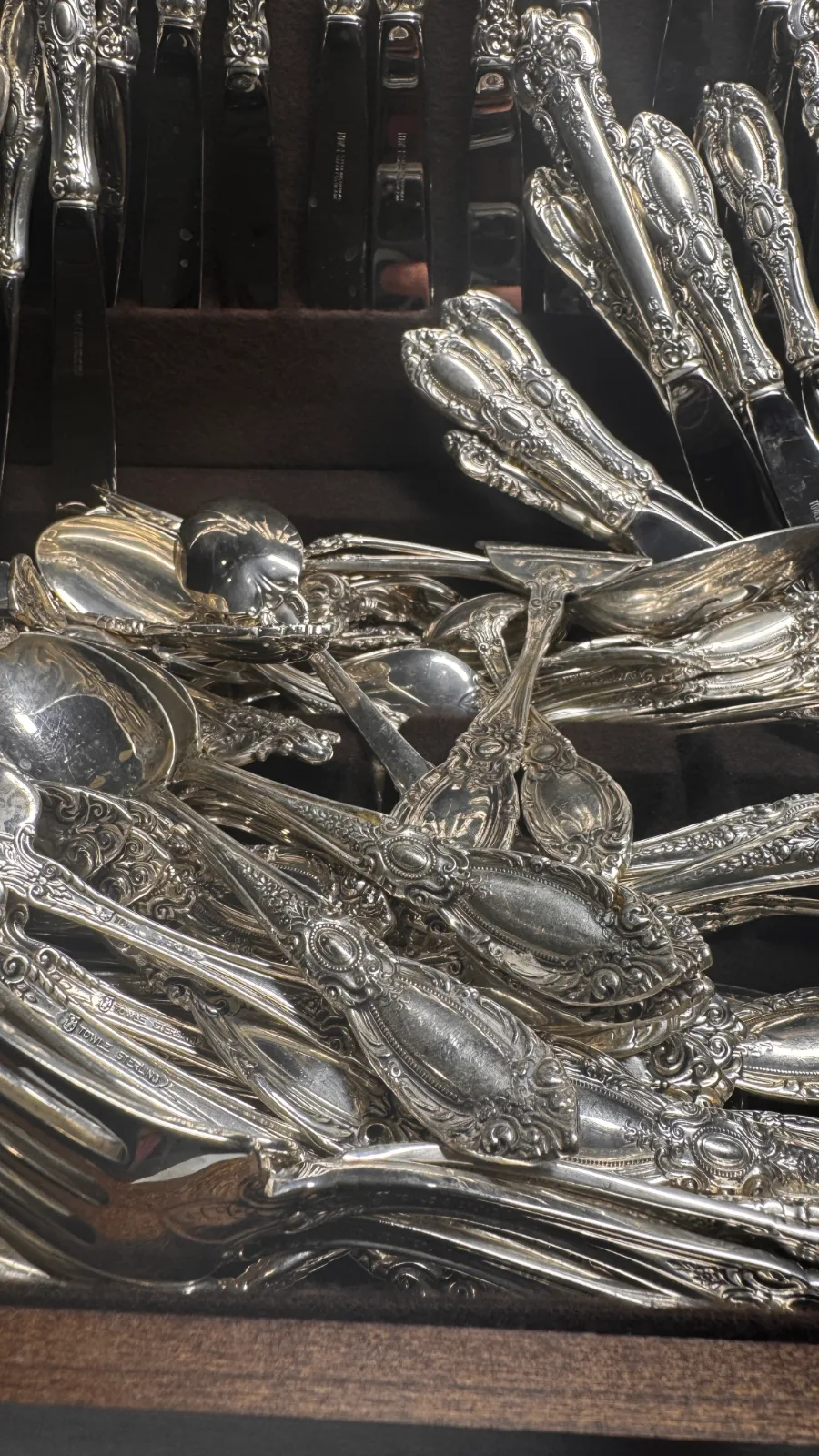 Close up of ornate silver spoons and forks piled in a tray