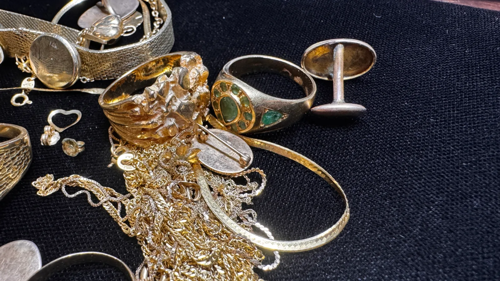 assorted gold rings chains and bracelets scattered on a dark surface