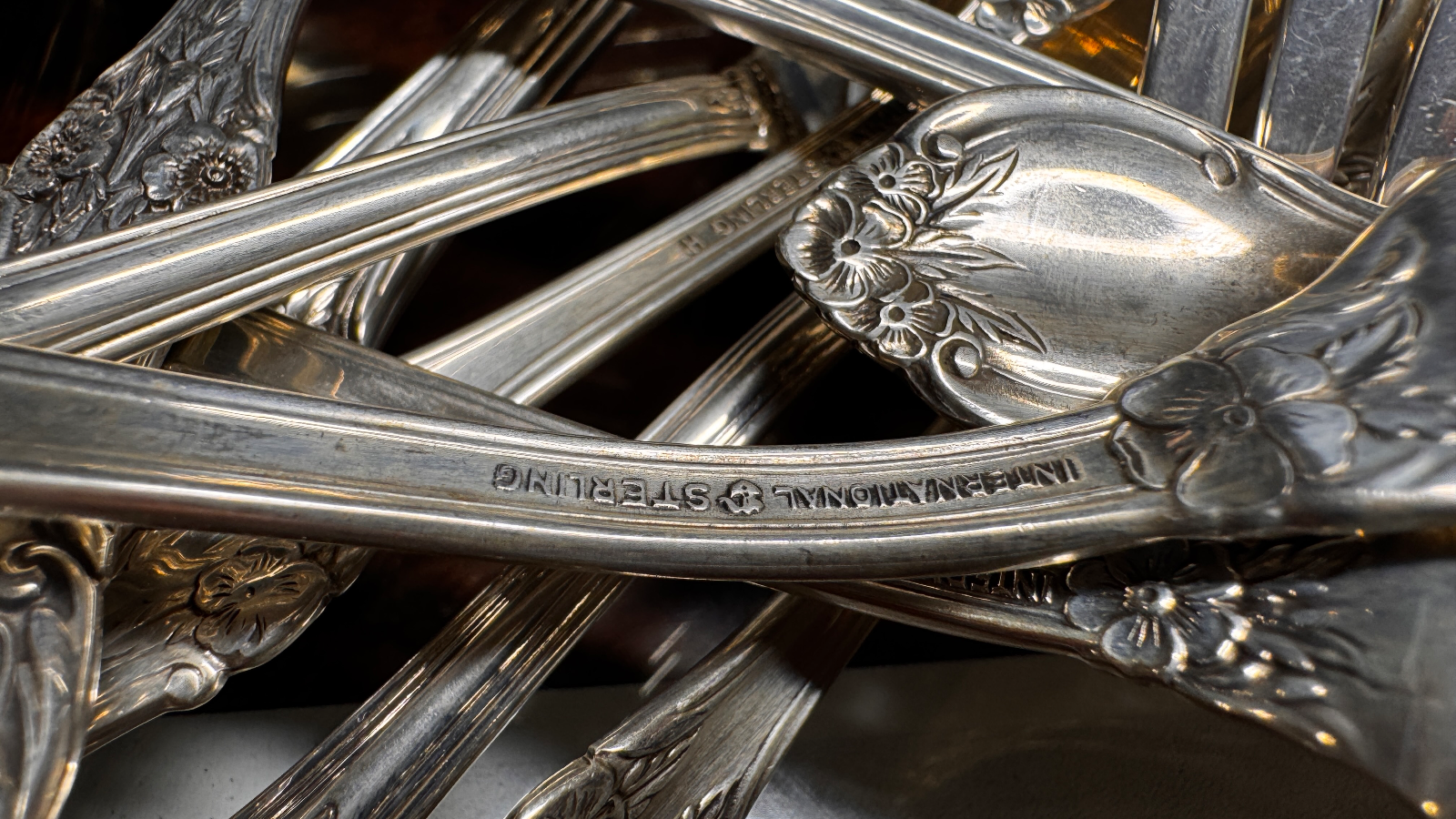 Close up of sterling silver cutlery with floral patterns and engraved text
